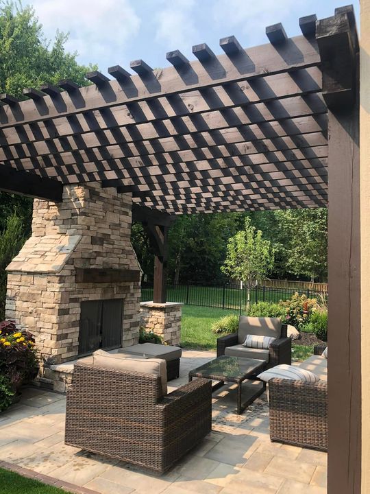 A Patio With Wicker Furniture And A Fireplace Under A Pergola – Olathe, KS - JJR Painting