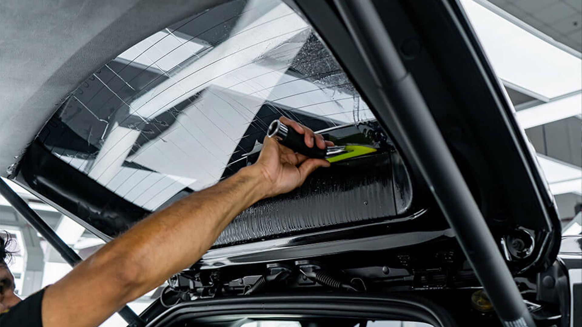 A man is working on the rear window of a car.