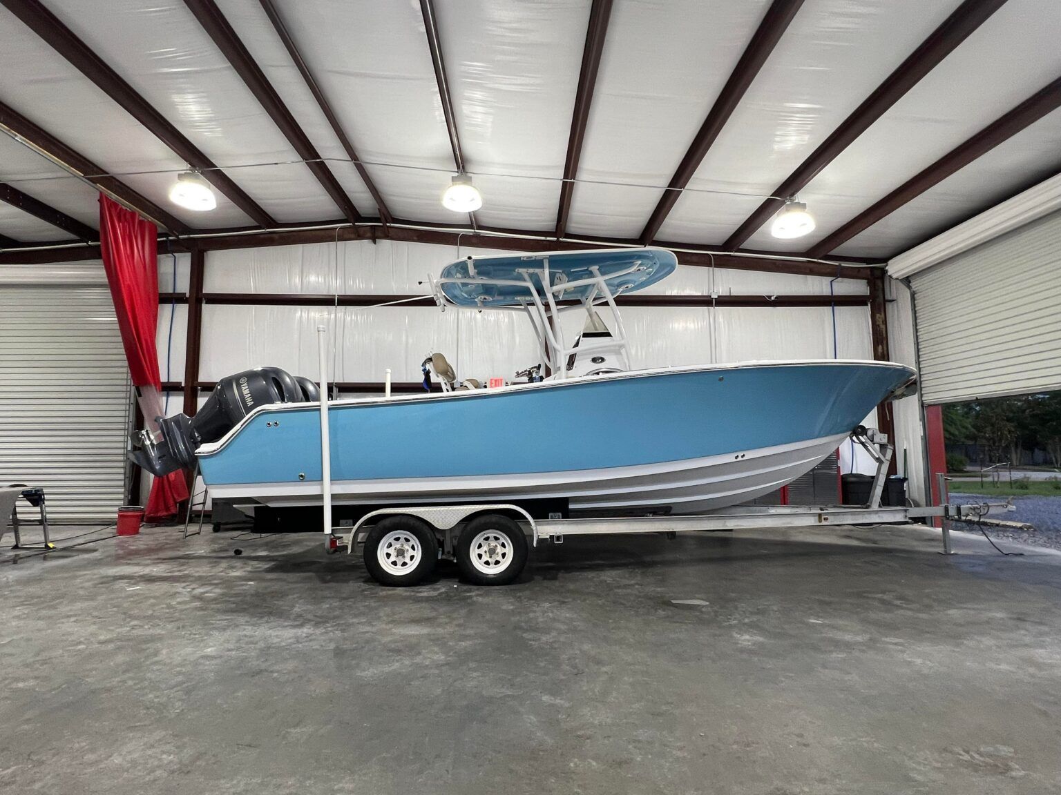 A blue boat is sitting on a trailer in a garage.