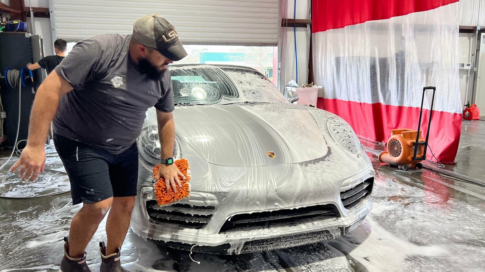 A man is washing a car in a car wash.