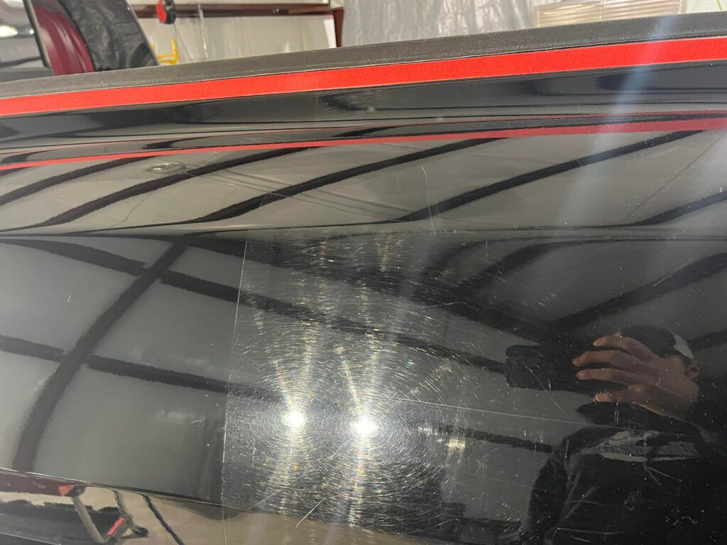 A person is taking a picture of a black car with a camera.