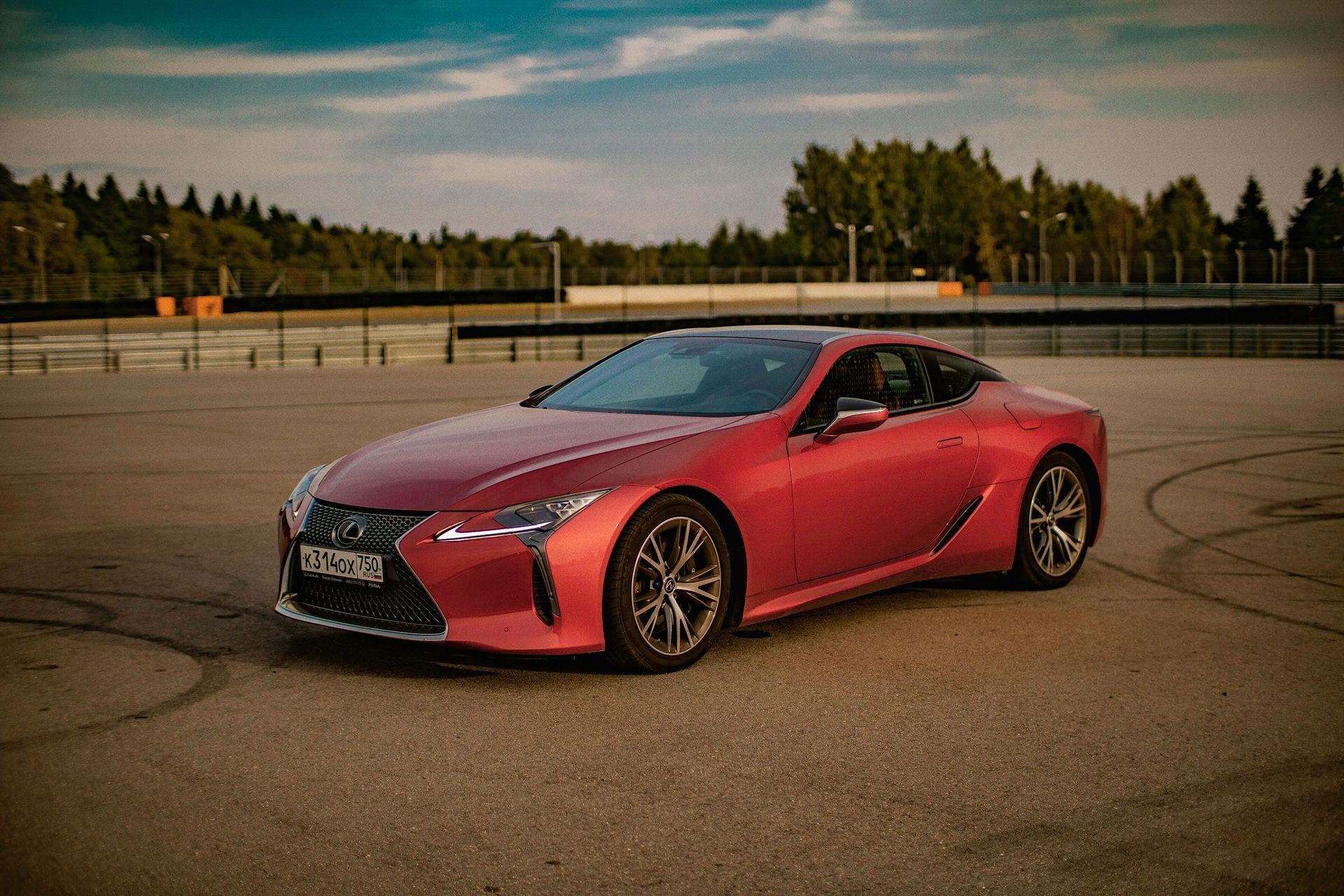 A white sports car is driving down a street at sunset.