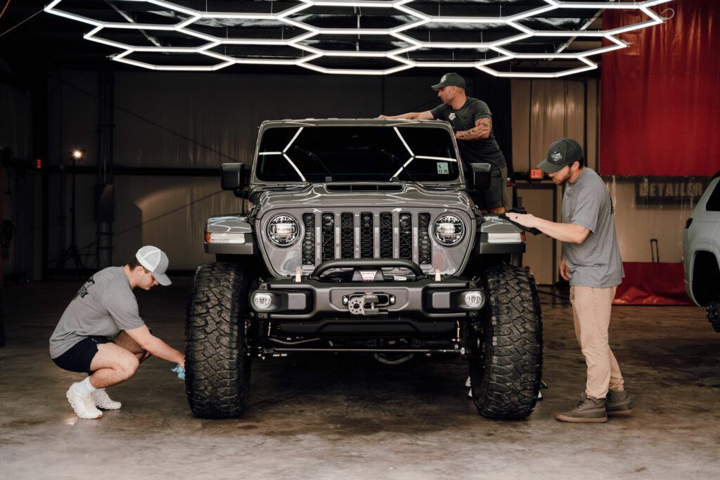 Two men are working on a jeep in a garage.