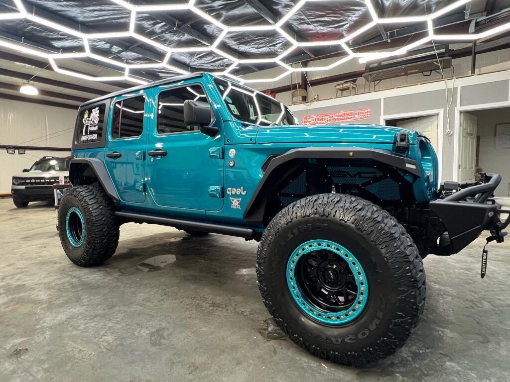 A blue jeep wrangler is parked in a garage.