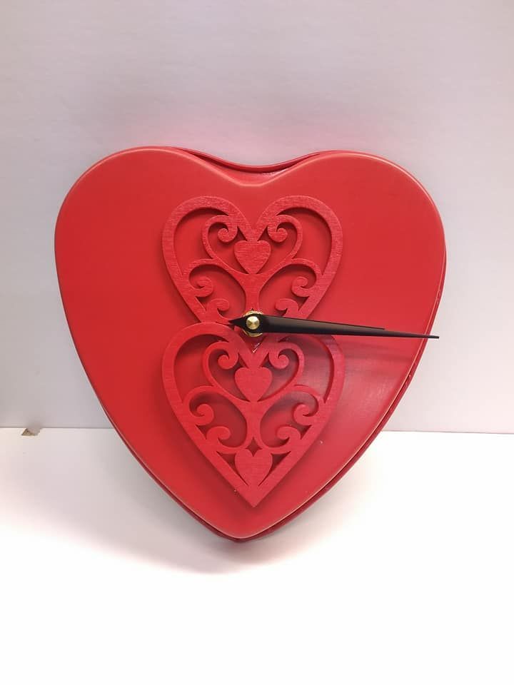 Red heart-shaped wall clock with a decorative cutout heart design and black clock hands.