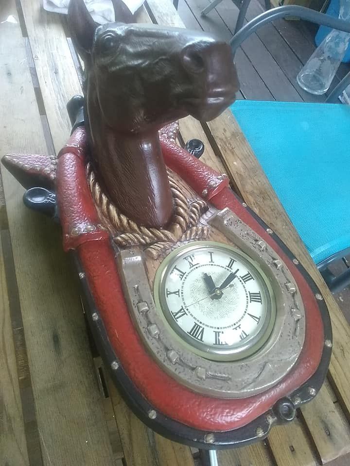 Horse head wall clock with red and brown accents, clock face is surrounded by a horseshoe design.