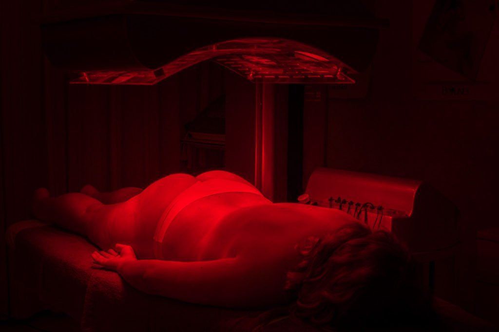 Una donna è sdraiata su un letto sotto una luce rossa.