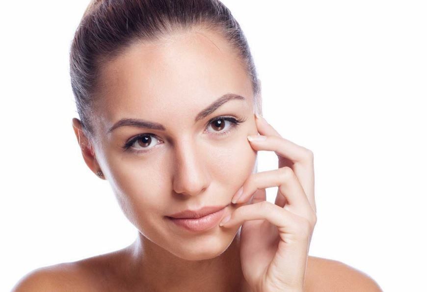 Una donna si tocca il viso con la mano e guarda la telecamera.