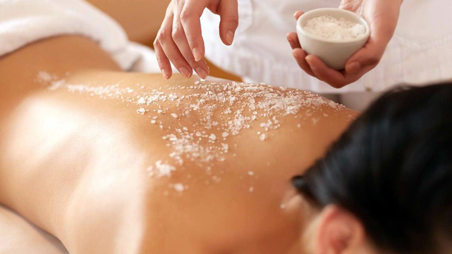 Una donna riceve un massaggio con sale marino sulla schiena.