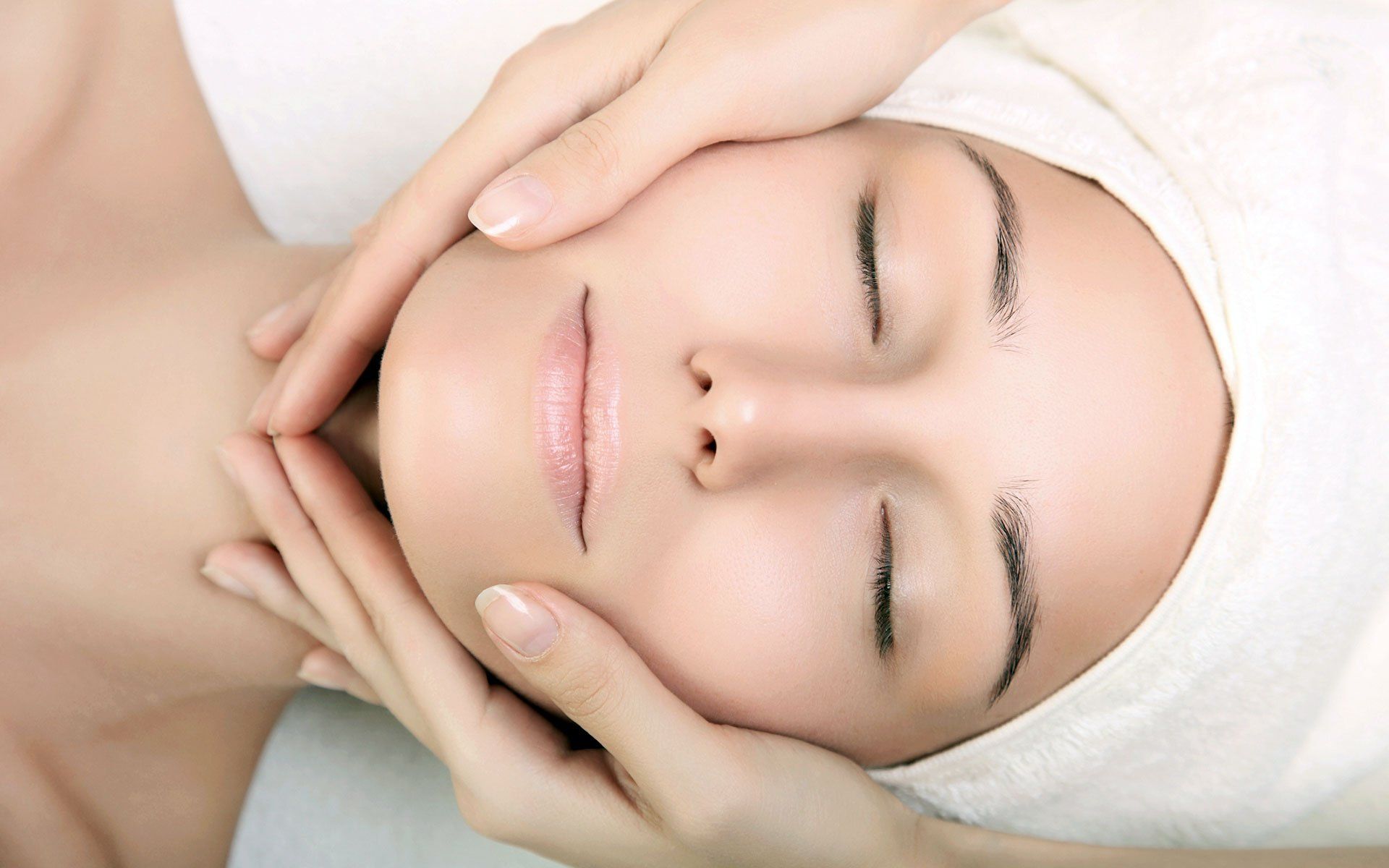 Una donna riceve un massaggio facciale con gli occhi chiusi.