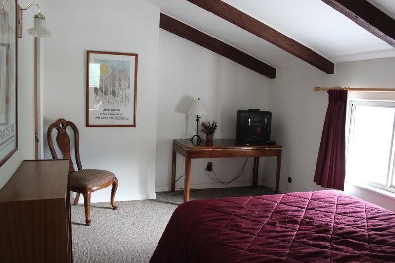 A bedroom with a bed a desk and a television