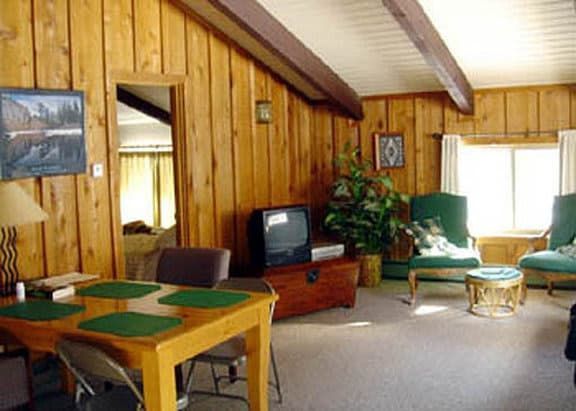 A living room with wood paneling and a table and chairs