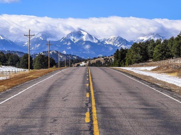 An empty highway with snowy mountains in the background.