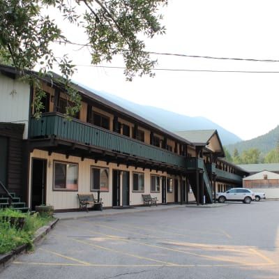 A white car is parked in front of a large building