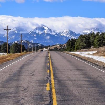 A road with mountains in the background and snow on the ground