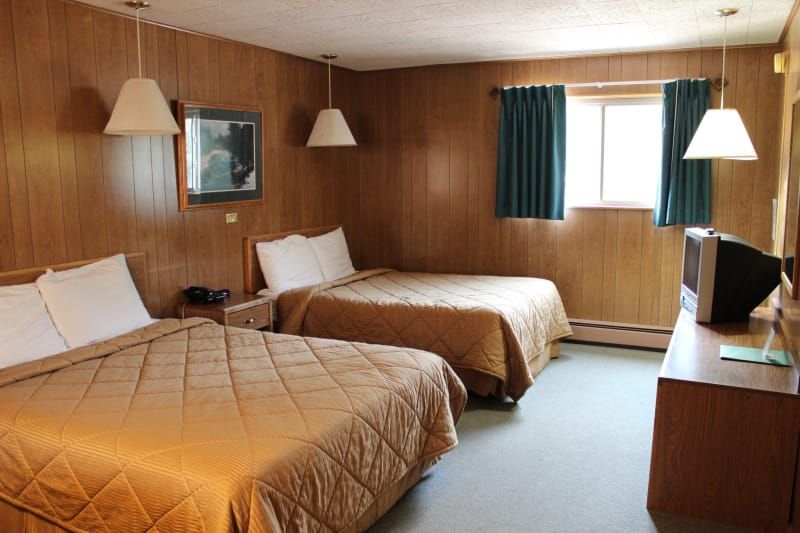 A hotel room with two beds and a television