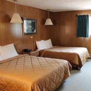 A hotel room with two beds and a picture on the wall.