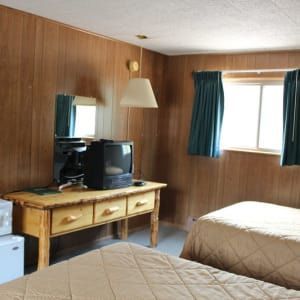 A hotel room with two beds and a television