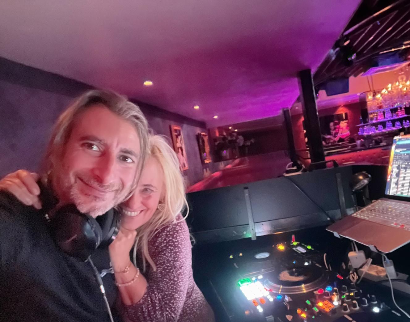 Ein Mann und eine Frau posieren vor einem DJ - Pult für ein Foto.