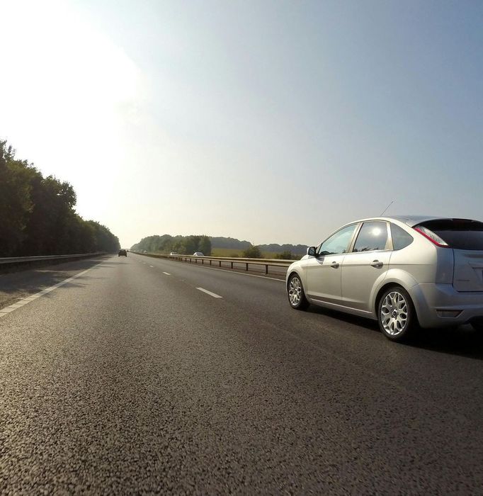 A silver car is driving down a highway