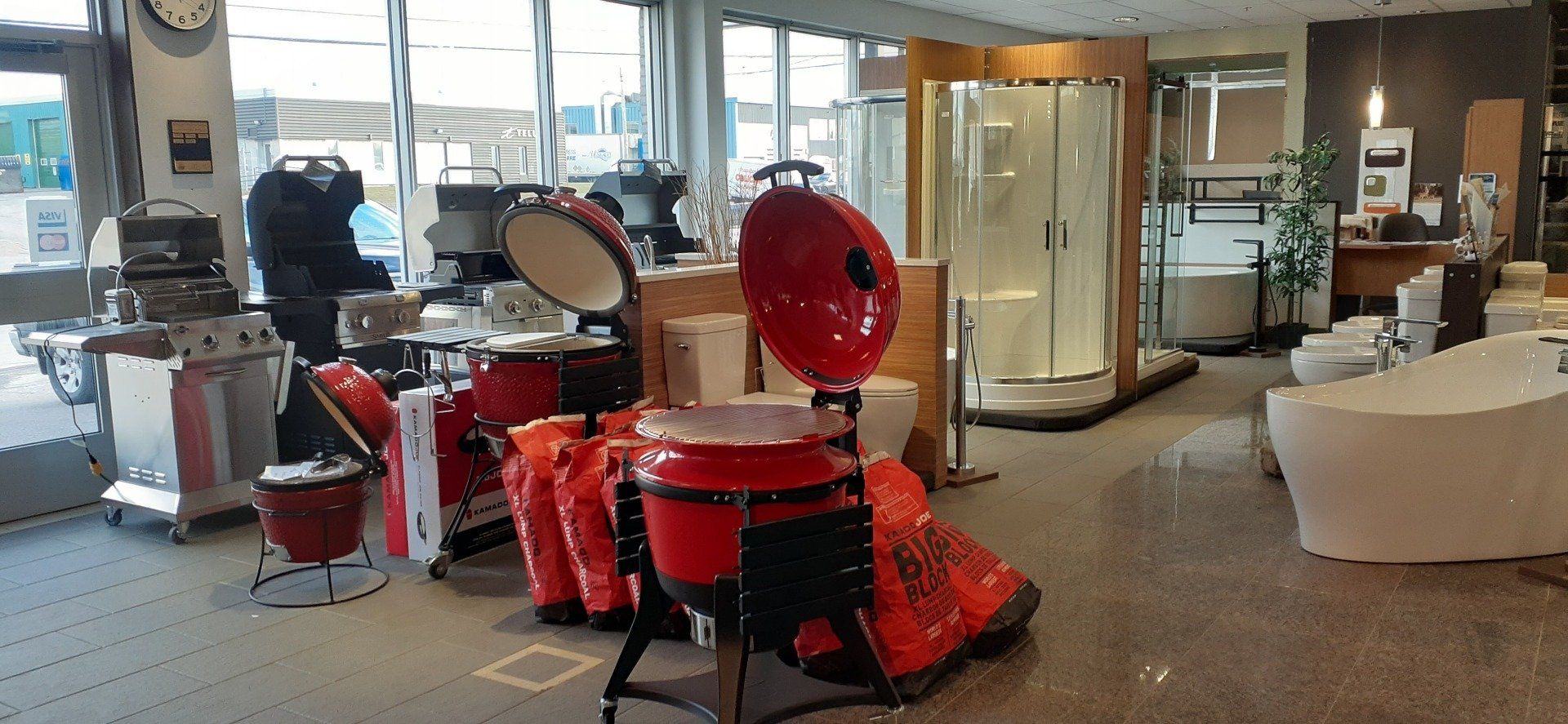 Une salle d'exposition remplie de nombreux appareils électroménagers et d'un gril rouge.