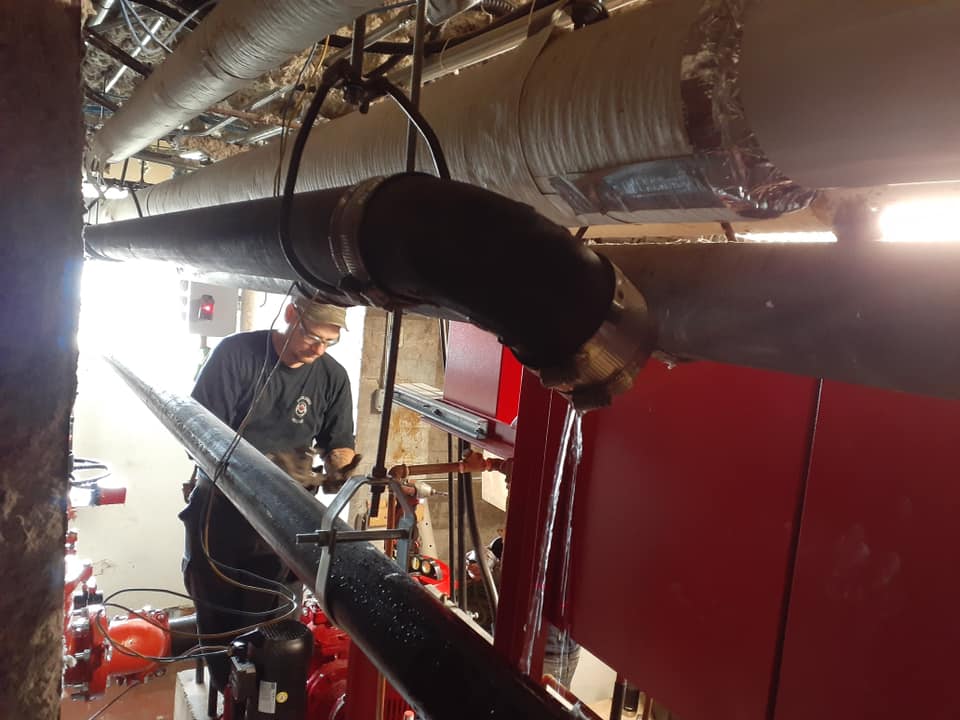 Un homme travaille sur un tuyau dans une pièce.