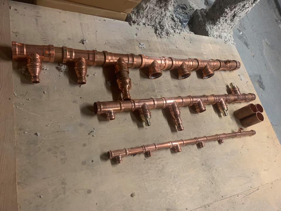 Un tas de tuyaux en cuivre sont posés sur une table en bois.