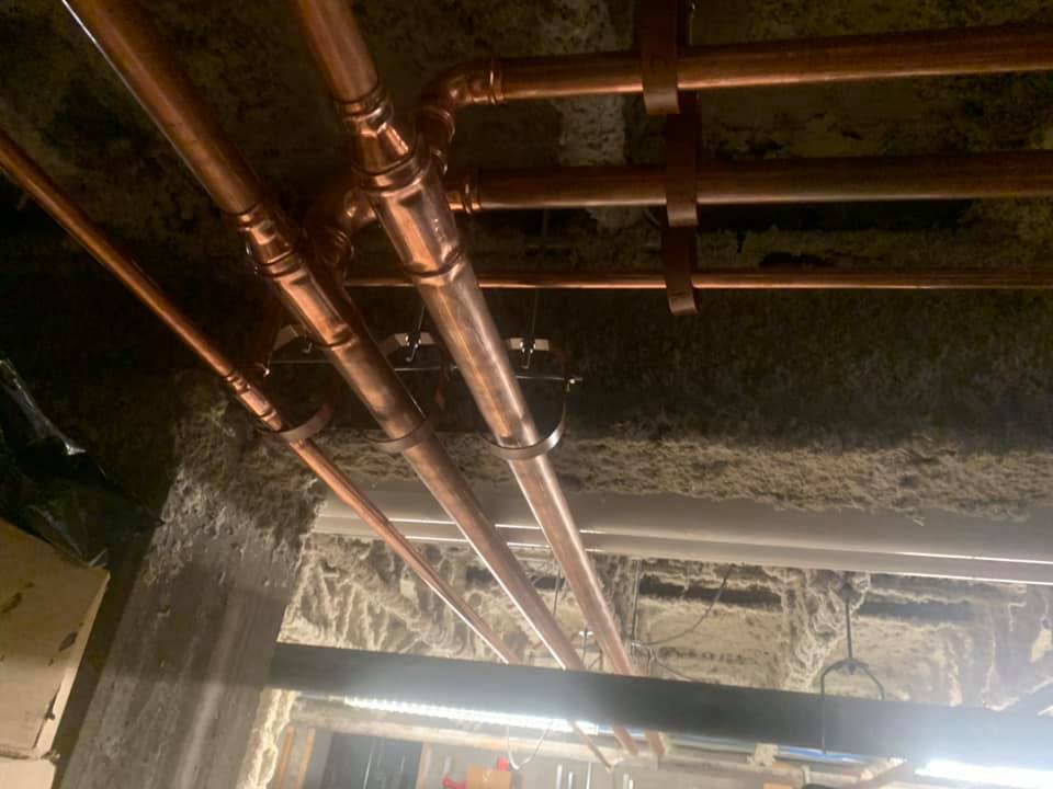 Un tas de tuyaux en cuivre pendent du plafond d'un bâtiment.