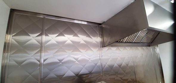 Une cuisine avec murs en acier inoxydable et hotte.