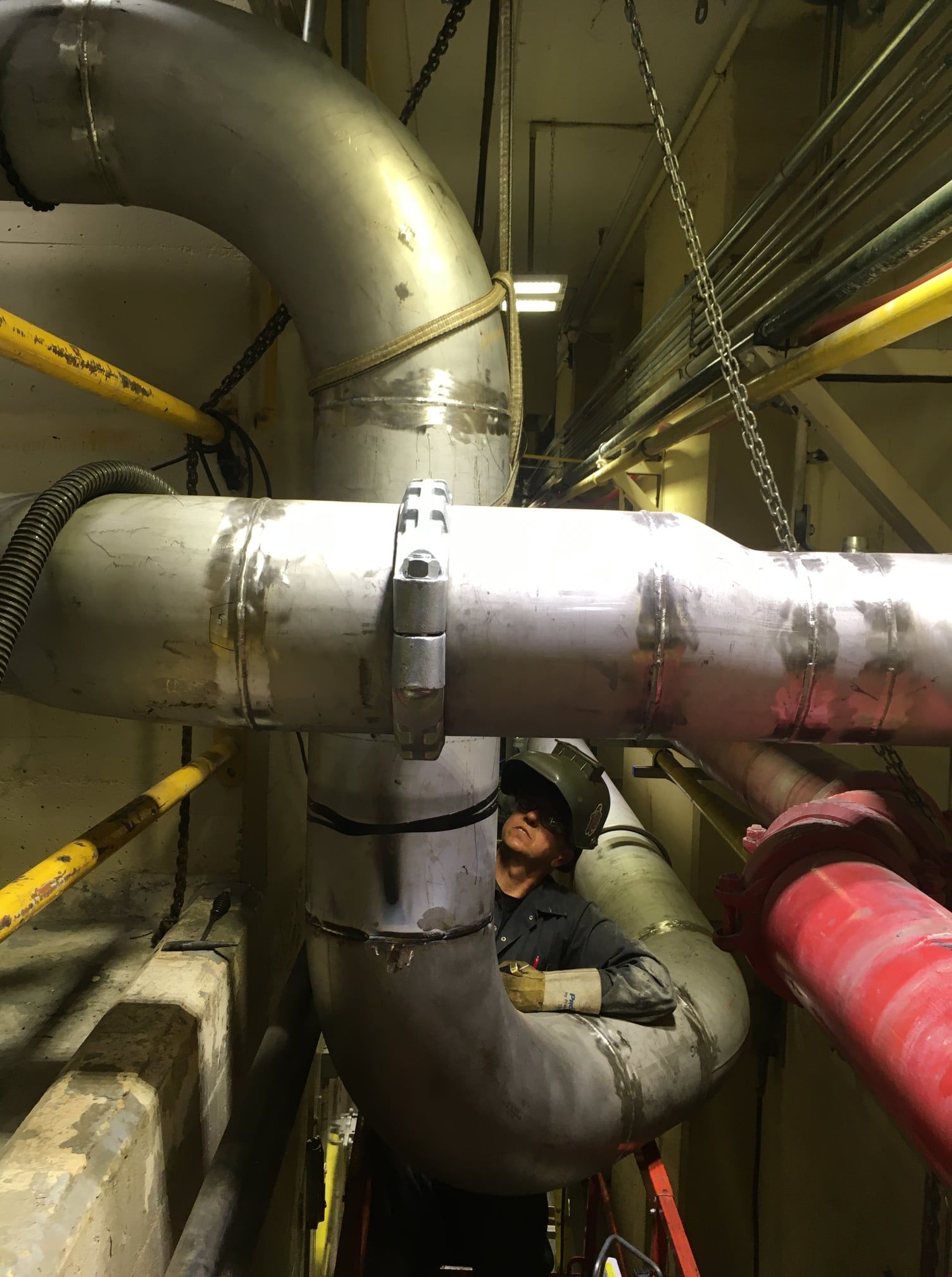 Un homme travaille sur un tuyau dans une usine.