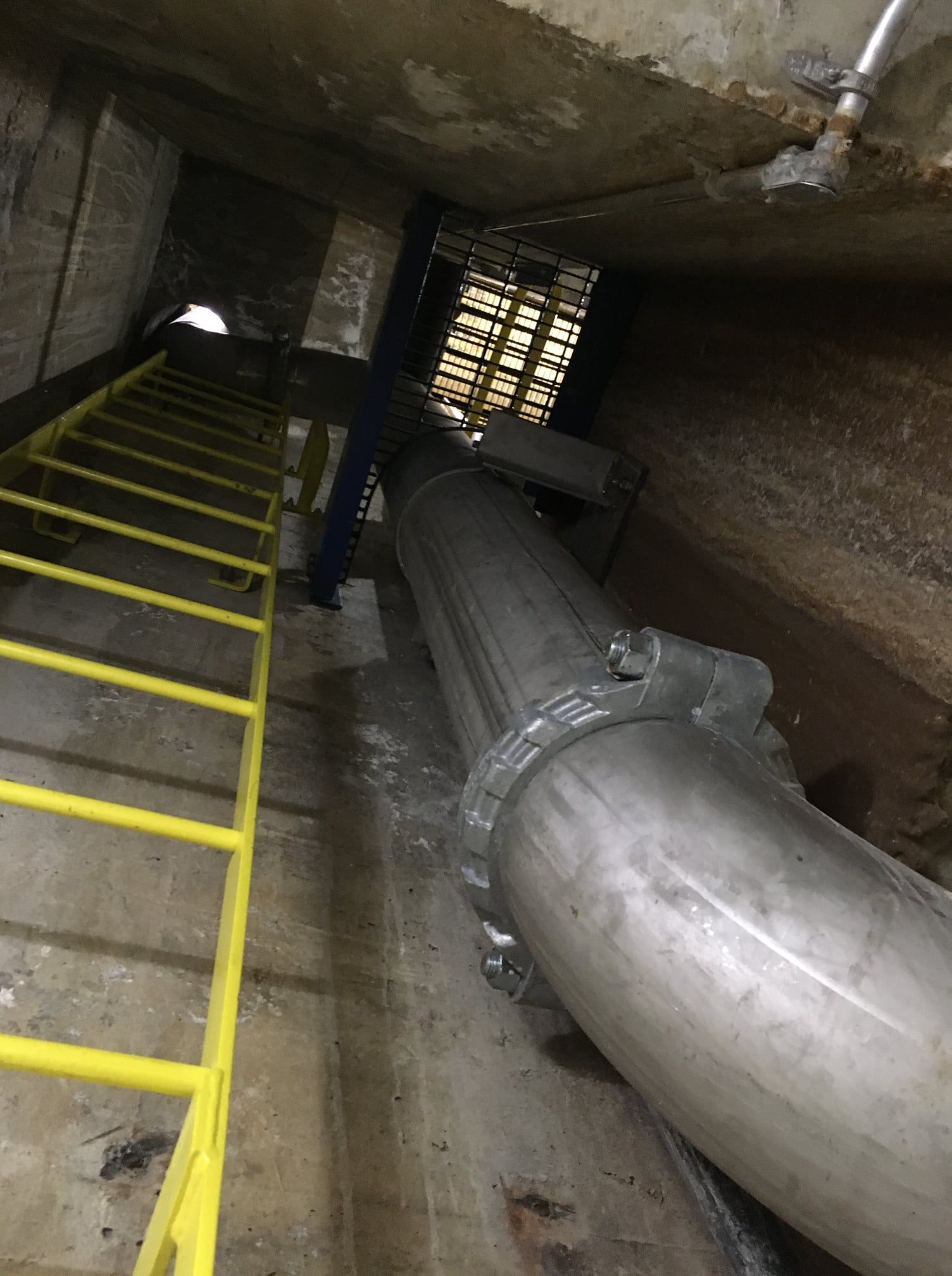 Une échelle monte jusqu'à un tuyau dans un tunnel.