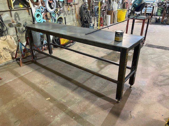 Une longue table en métal est posée dans un garage à côté d'une chaise.