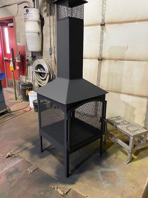 Une cheminée noire est assise dans un garage à côté d'un tabouret