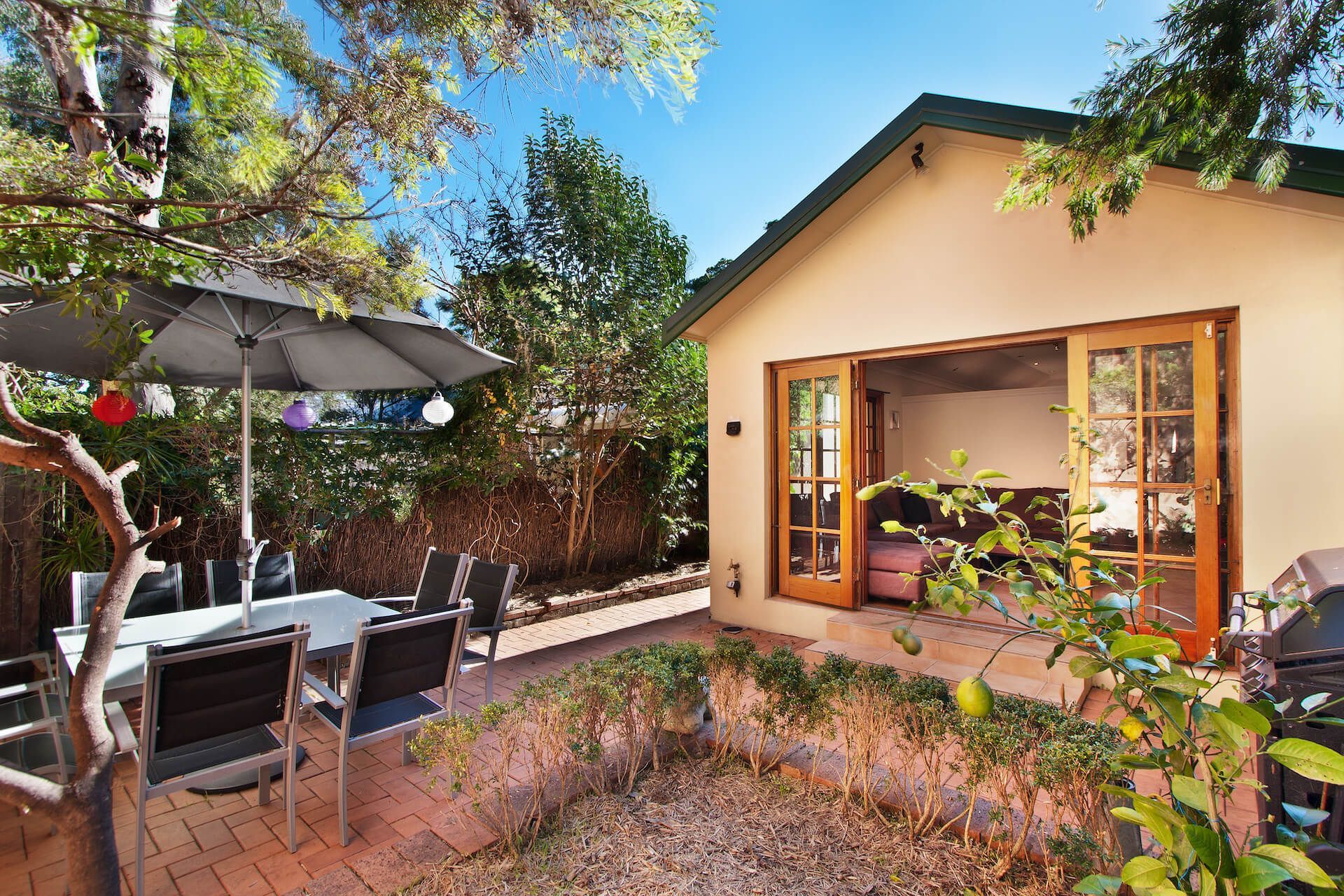 A patio with a table and chairs and an umbrella in front of a house