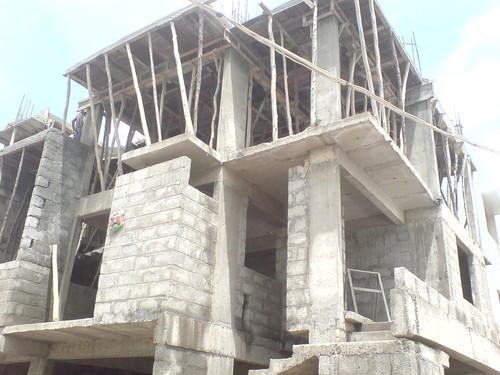 Building under construction with concrete walls and wooden scaffolding.