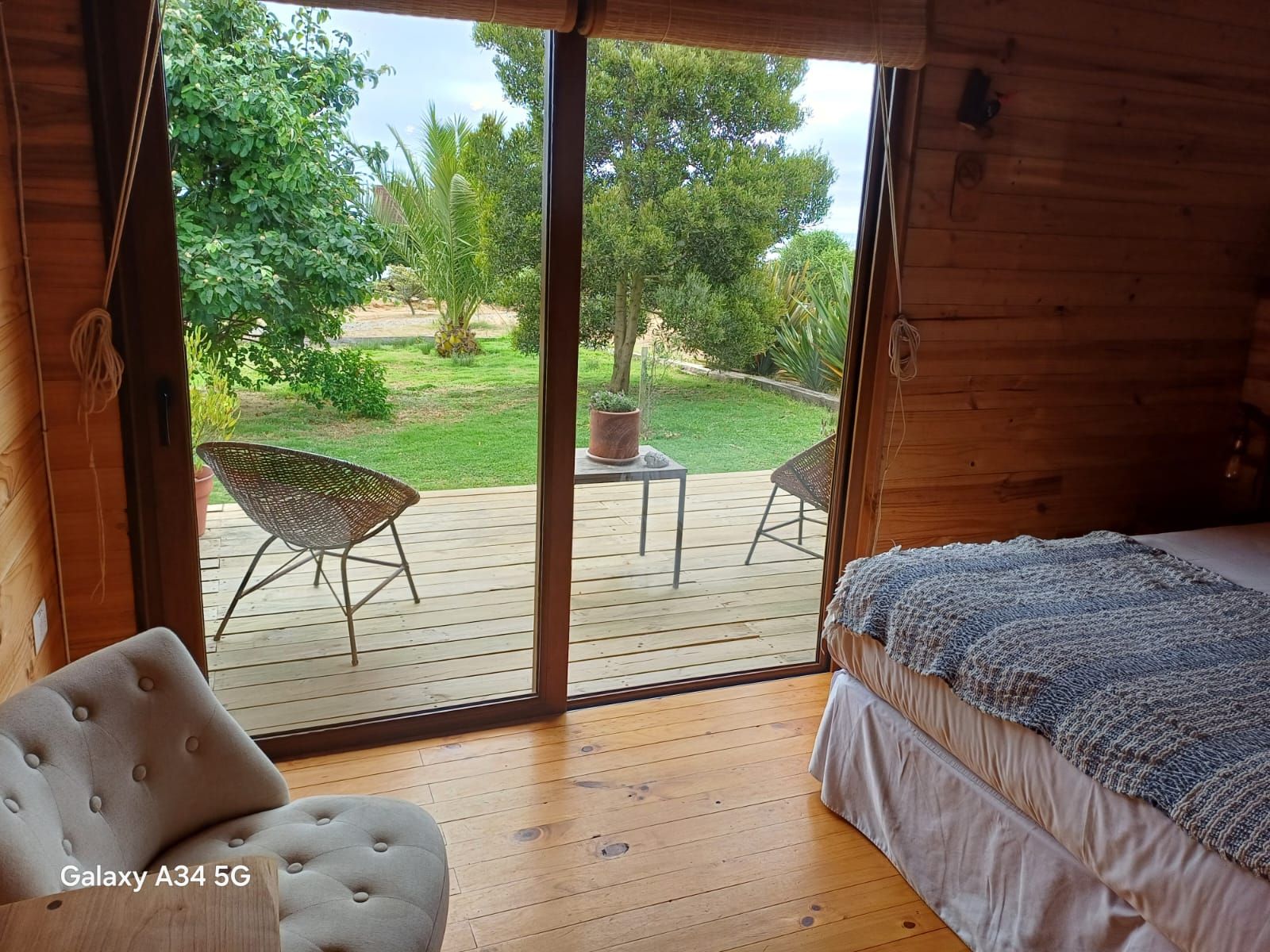 Dormitorio con paredes de madera, vista a un patio a través de puertas corredizas y una cama.