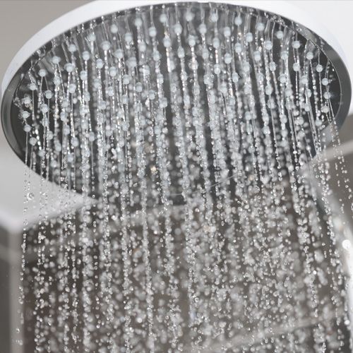 Cabezal de ducha con gotas de agua que fluyen hacia abajo.