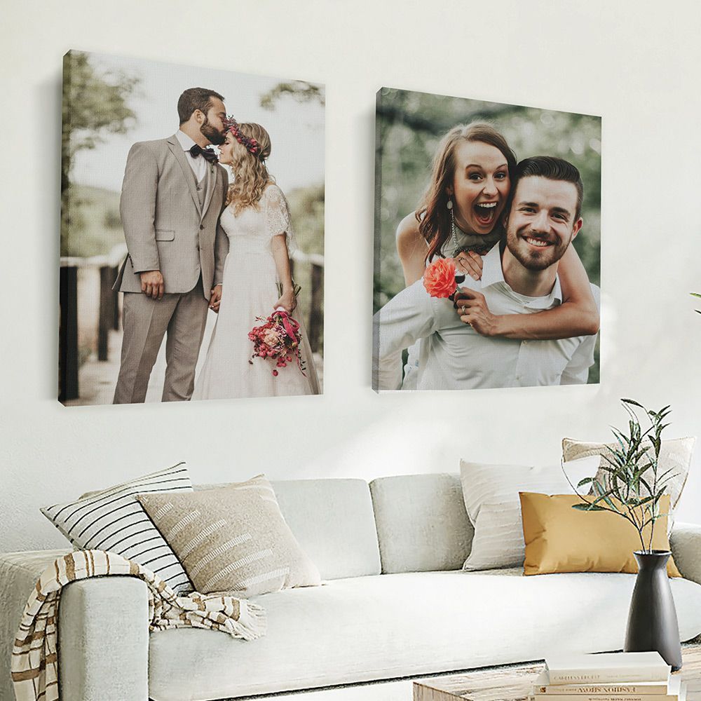 Two canvas prints featuring photos of couples hanging on a white wall above a white couch with pillows in a modern living room