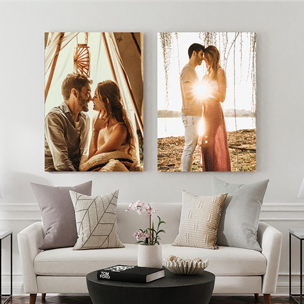 Image of two posters featuring couples about to kiss, hanging on an off white wall above a white couch with pillows on it in a modern living room