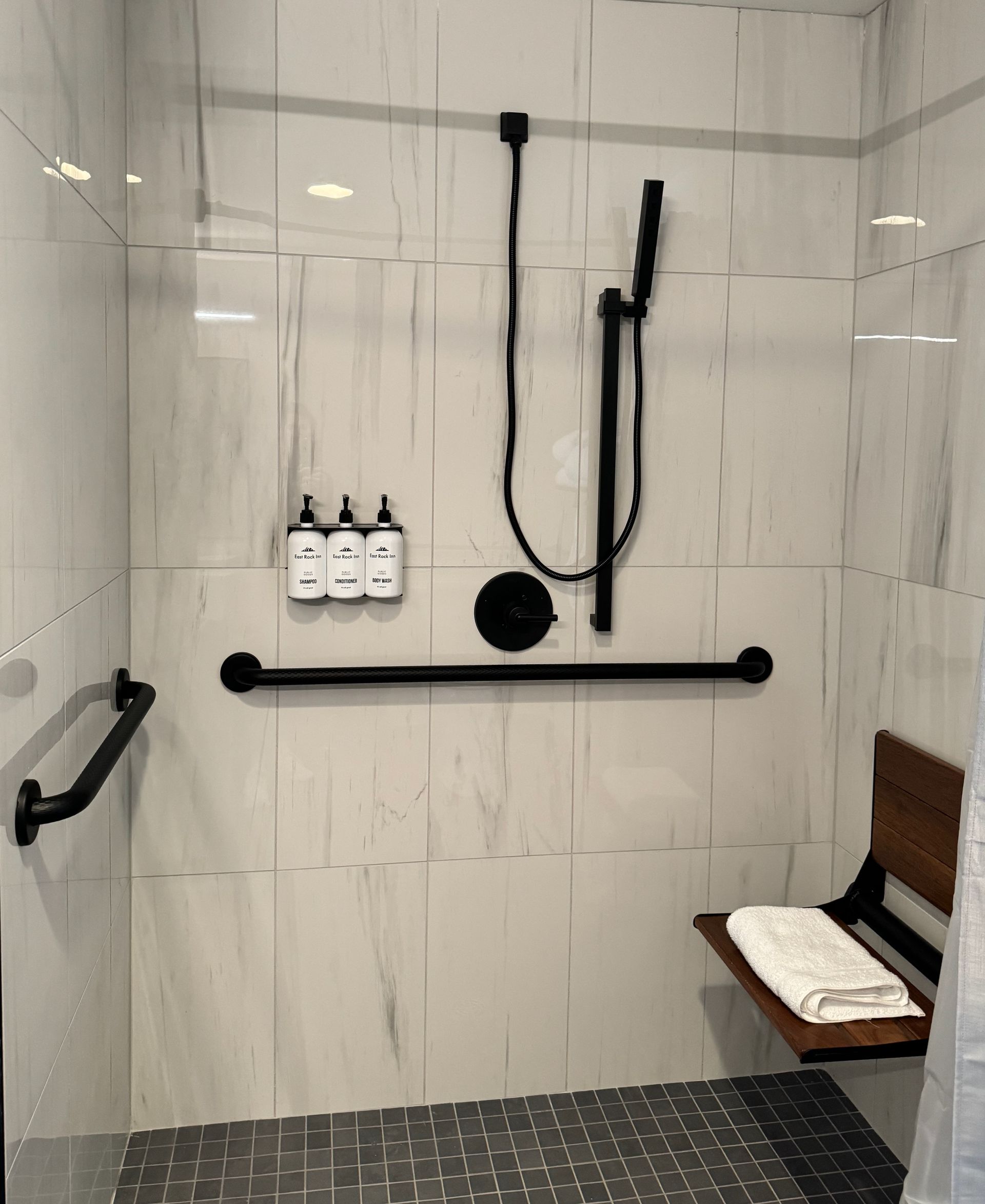 A bathroom with a walk in shower and a wooden bench