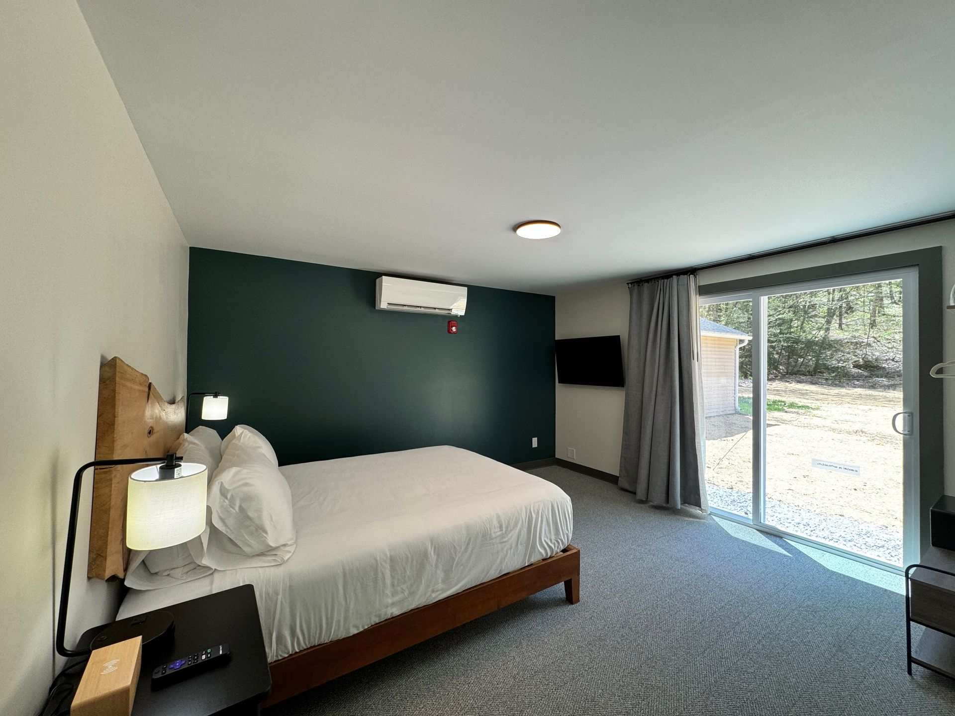 A hotel room with a king size bed and a sliding glass door.
