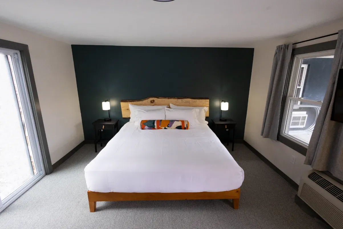 A hotel room with a king size bed and two windows