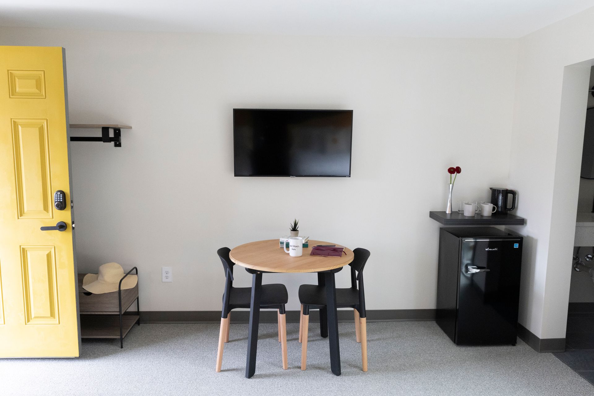 A room with a table and chairs and a flat screen tv on the wall.