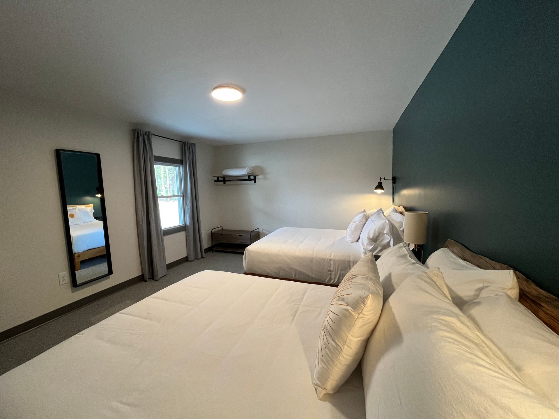 A hotel room with two beds and a mirror.