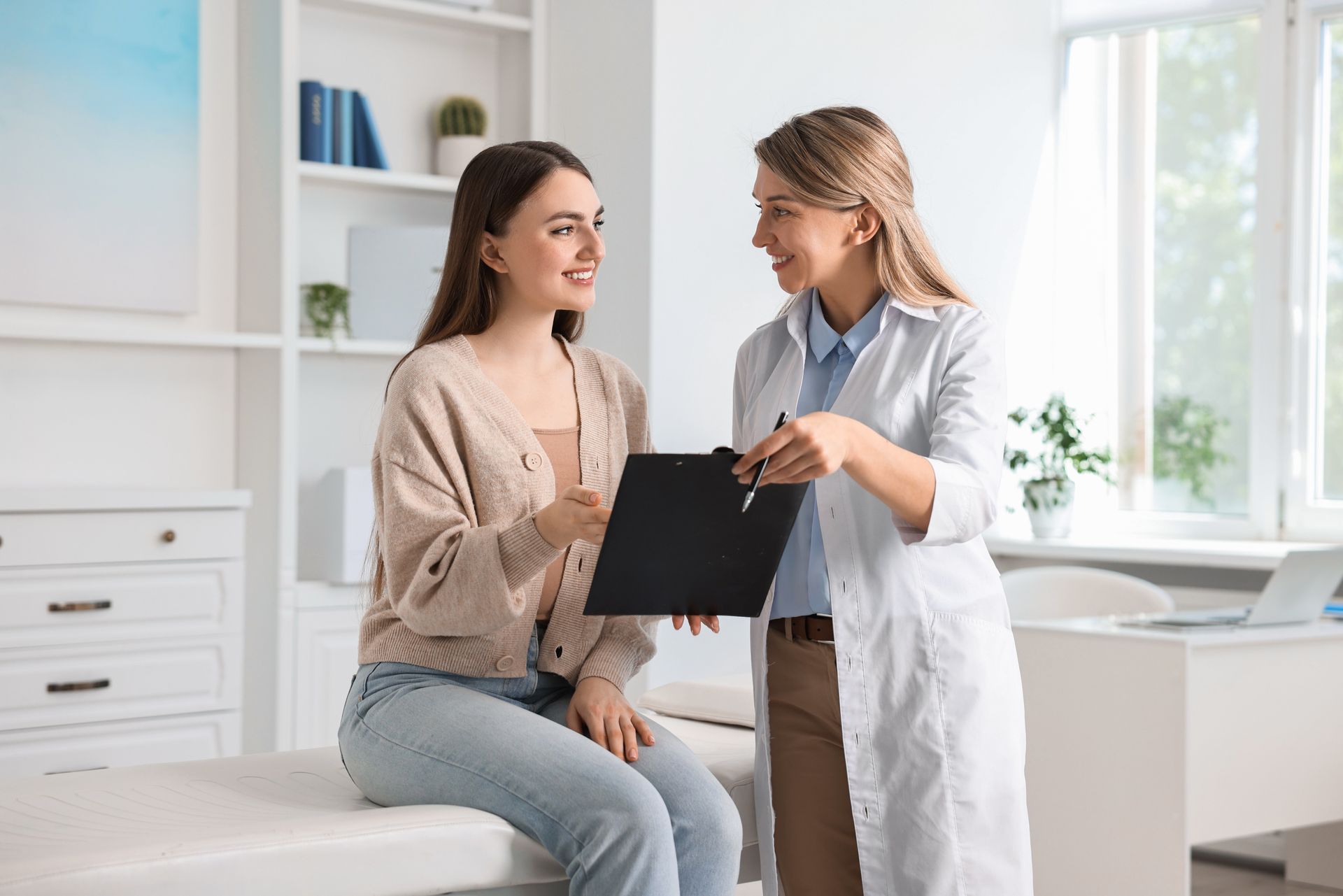 A doctor and patient discuss paperwork in a bright medical office.