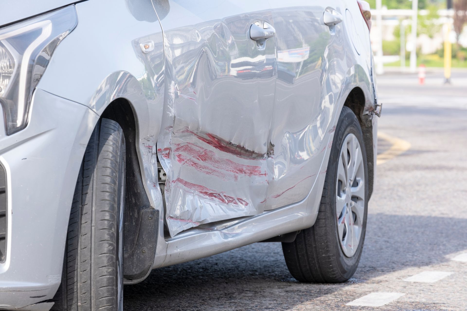 Silver car with significant damage to the side door and body, likely from a collision.