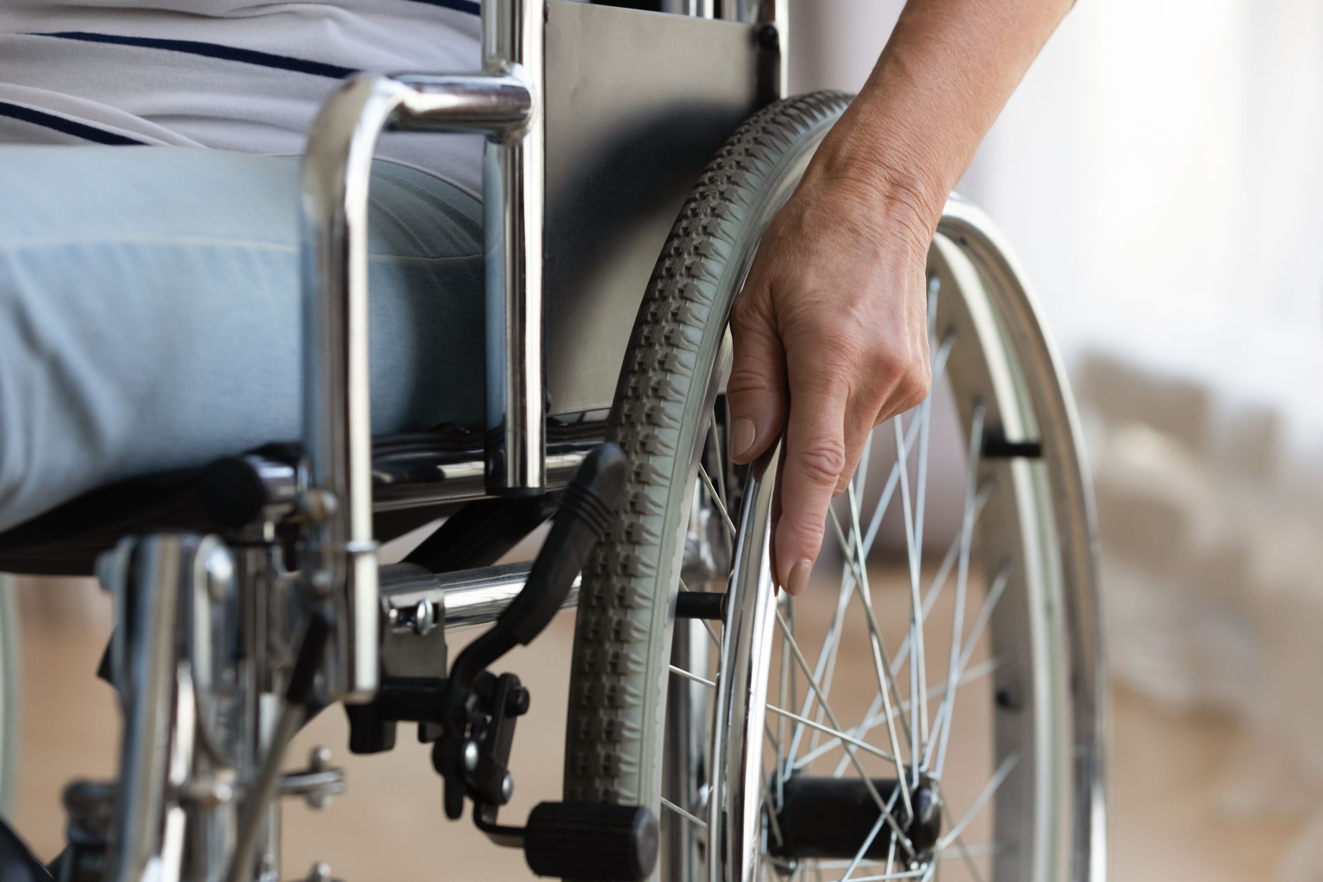 Hand on wheelchair wheel, person seated.