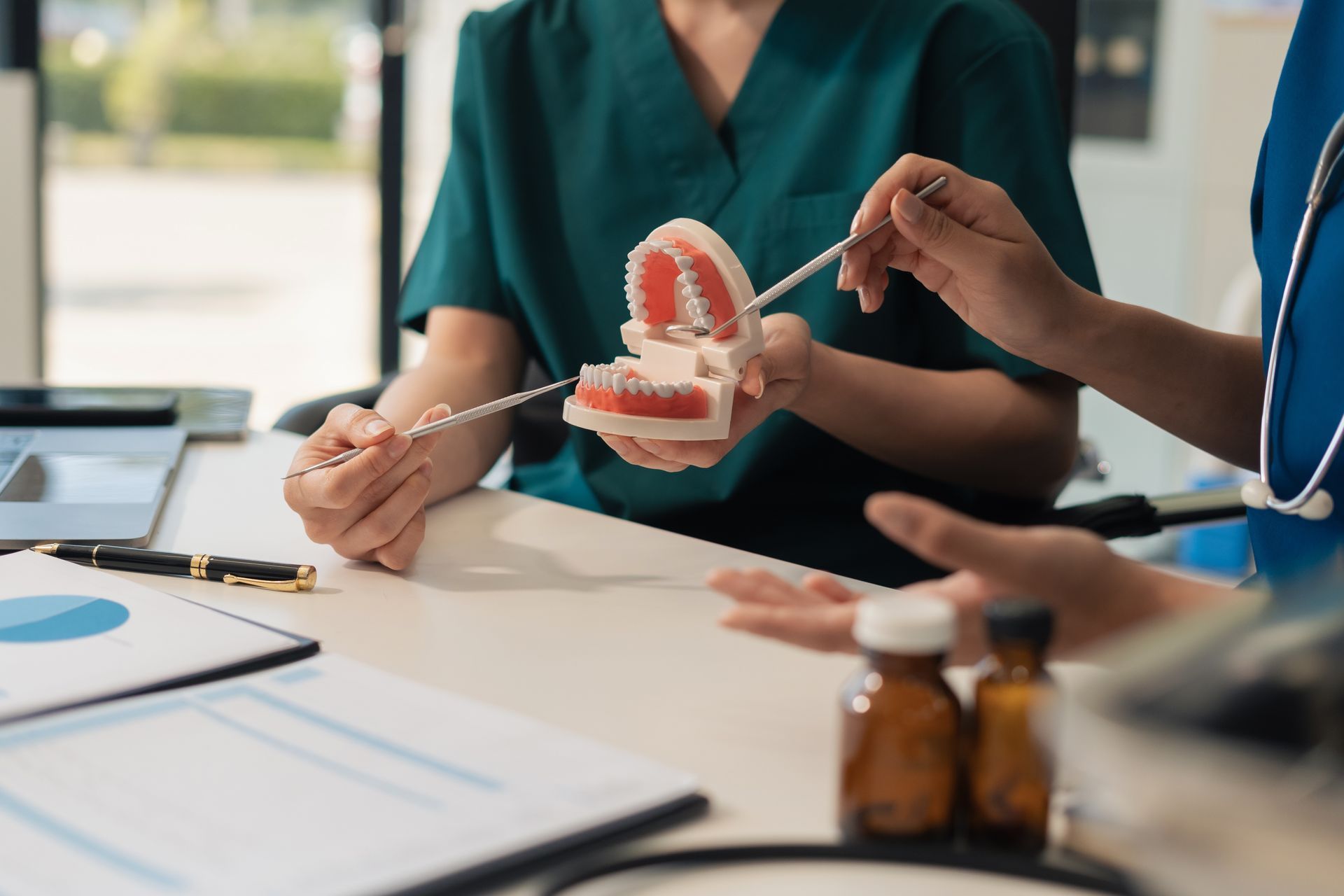 Two healthcare workers examining a dental model at a desk, discussing treatment options.
