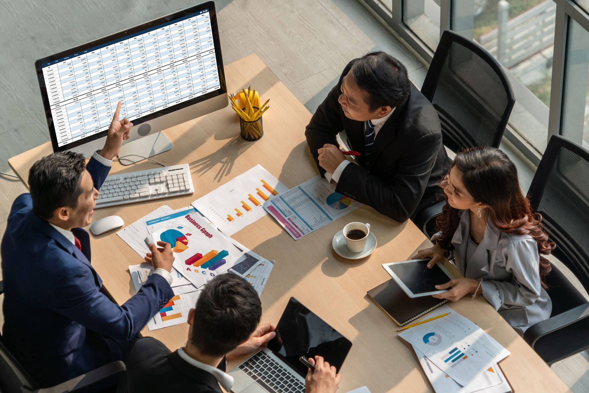 Business colleagues review data, charts and spreadsheets around a conference table.