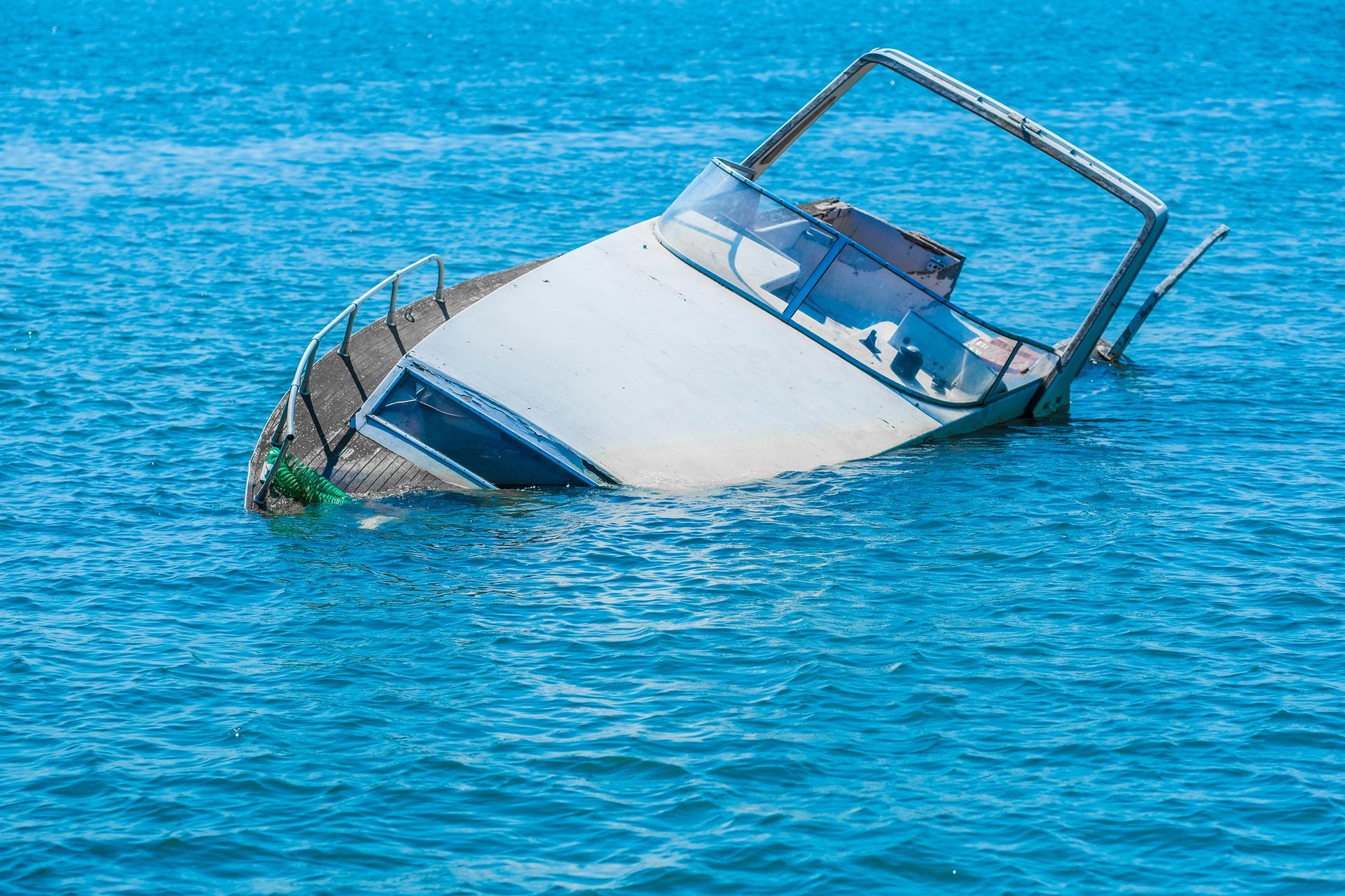 Partially submerged white boat in blue water.